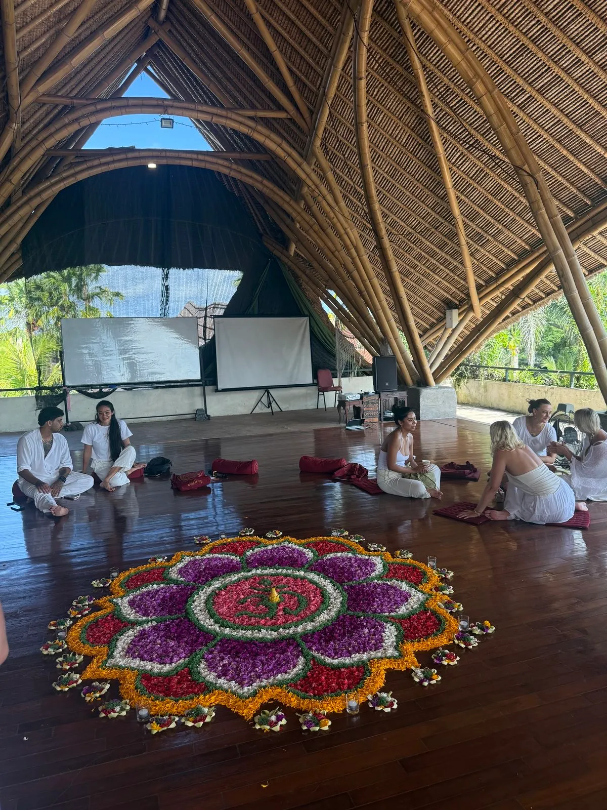 Grupo reunido en círculo alrededor de un mandala de flores durante una ceremonia